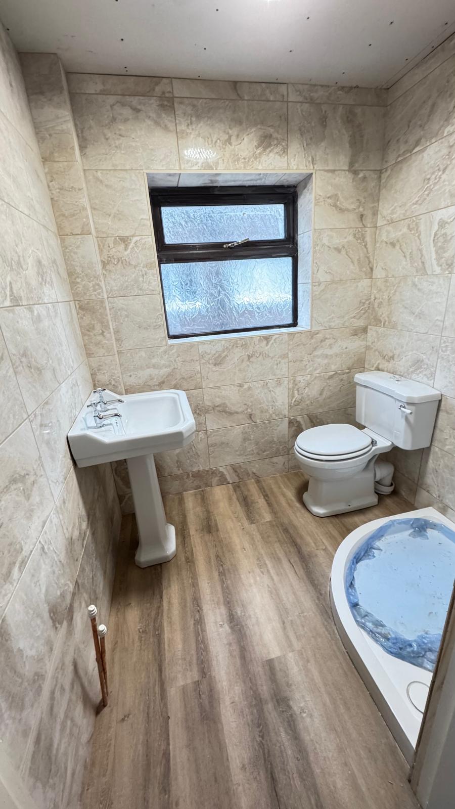 Bathroom with marble-effect tiles, pedestal basin and wood-effect floor